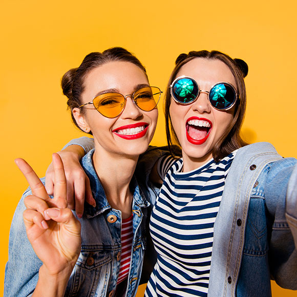 Two glad positive grinning ladies posing for a selfie with glasses