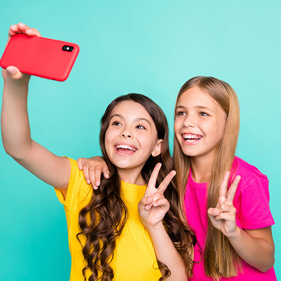 Photo of two excited girls wearing t-shirts yellow and pink spending free time recording videos